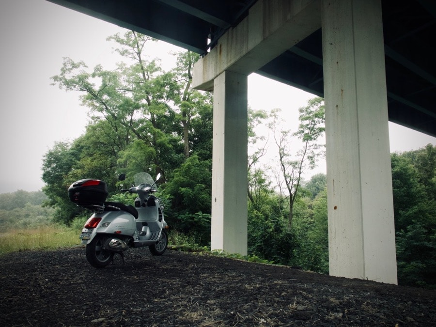Vespa GTS scooter parked under freeway overpass
