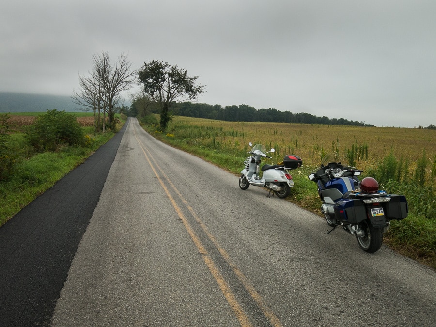 Vespa GTS scooter and BMW R1200 RT along rural road