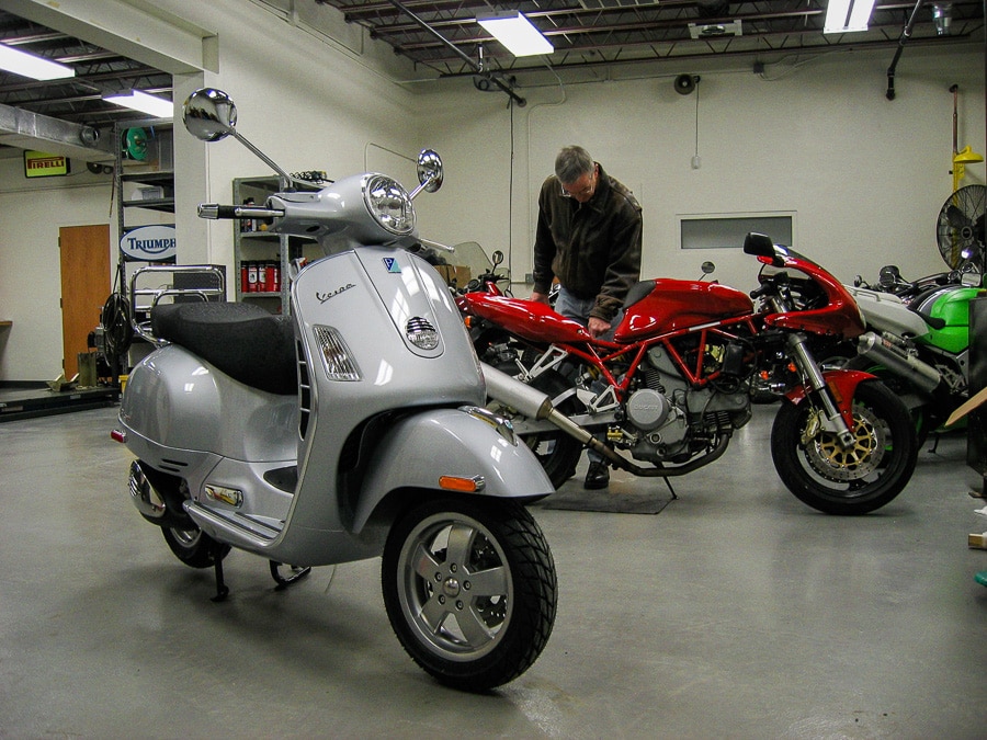 Vespa GTS scooter and Ducati motorcycle in shop