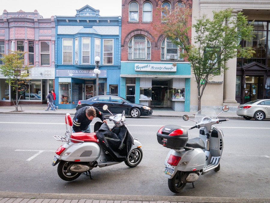 Two Vespa scooters parked along a city street.