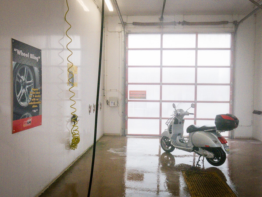Vespa GTS scooter in a car wash bay.