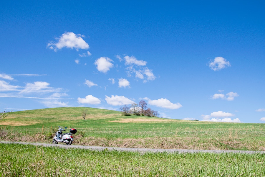 Vespa GTS scooter in rural landscape.