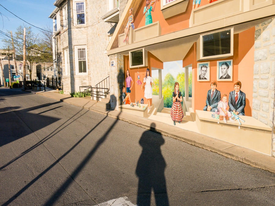 Man's shadow and mural on building.