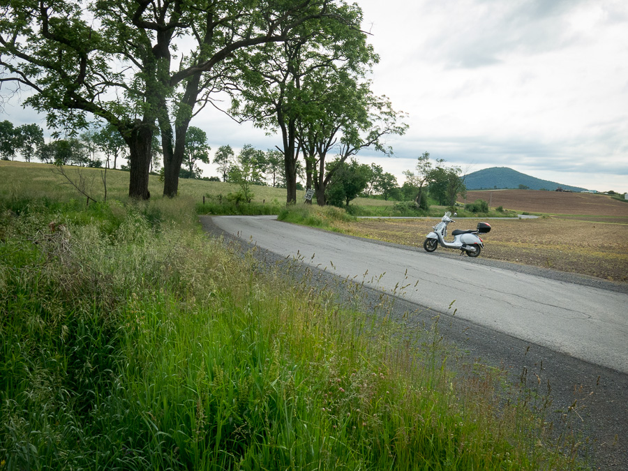 Vespa GTS scooter parked along a rural road.