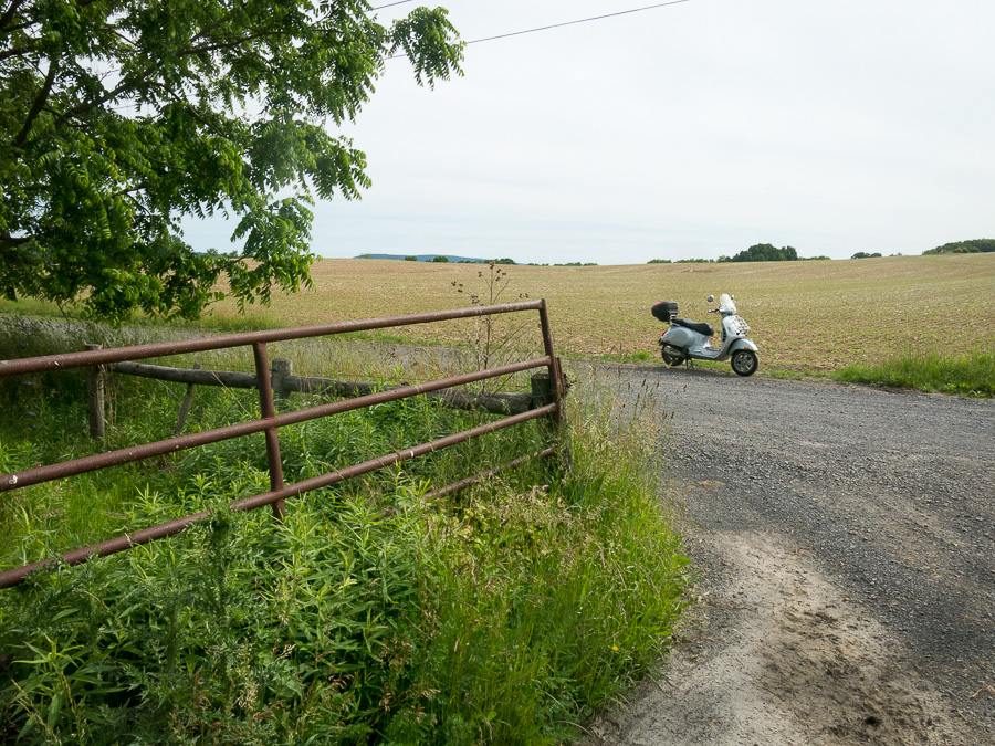 Vespa GTS scooter on a rural gravel road.