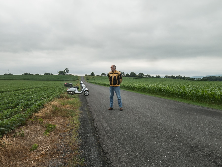 Steve Williams standing in the road with his Vespa