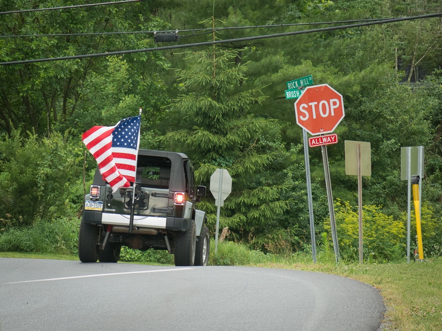 Jeep at intersection with American Flag flying from bumper