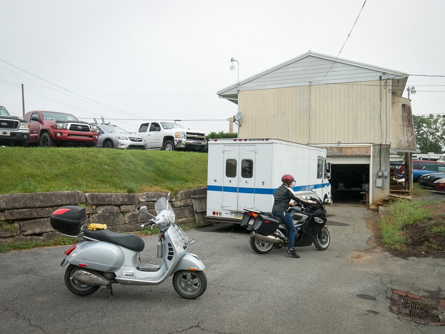 Scooter and motorcycle being moved outside of a garage