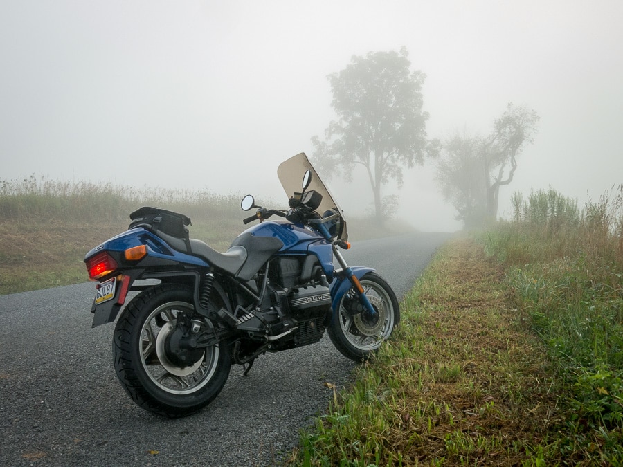 BMW K75 motorcycle on a foggy, rural road.