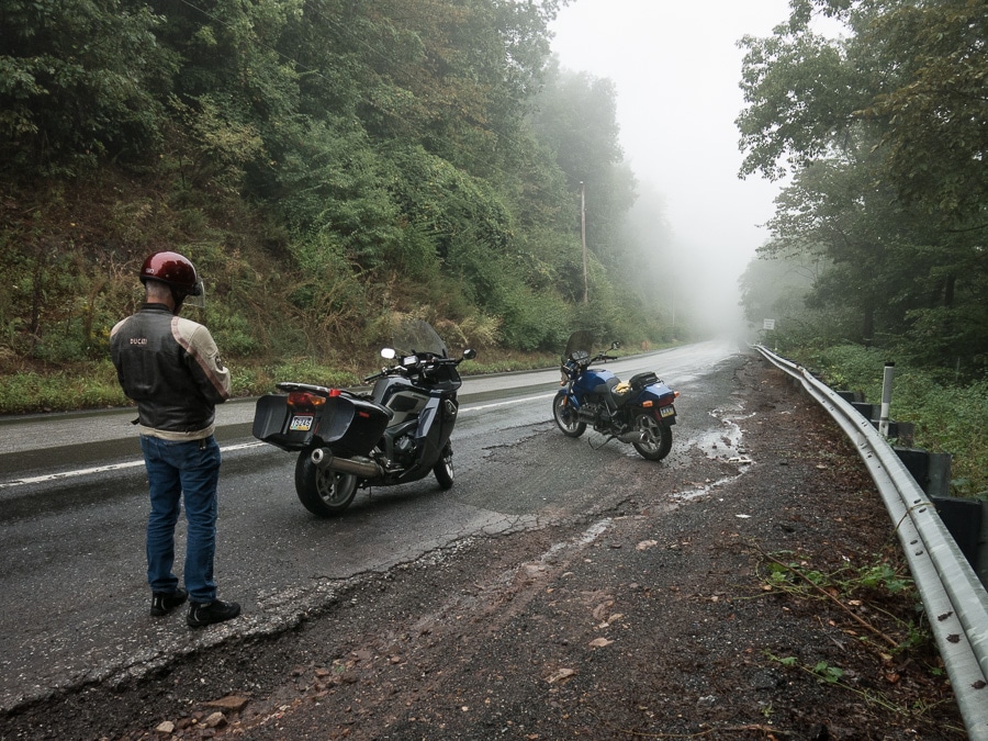 Motorcycles parked along a foggy road.