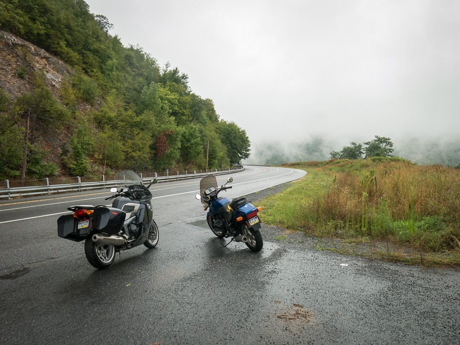 BMW motorcycles parked along a rainy road.