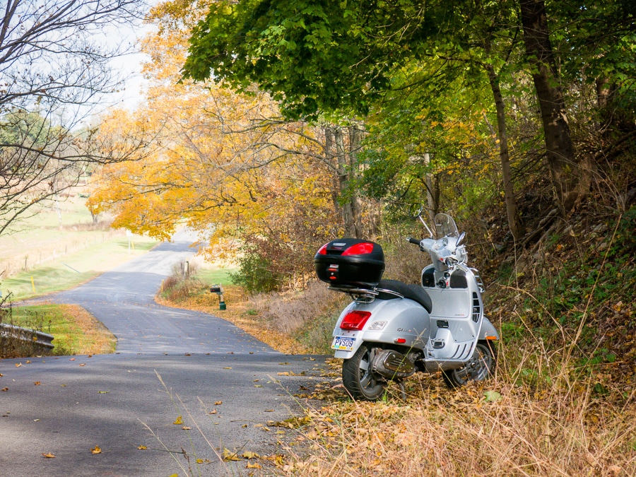 Vespa scooter along a rural road in autumn.