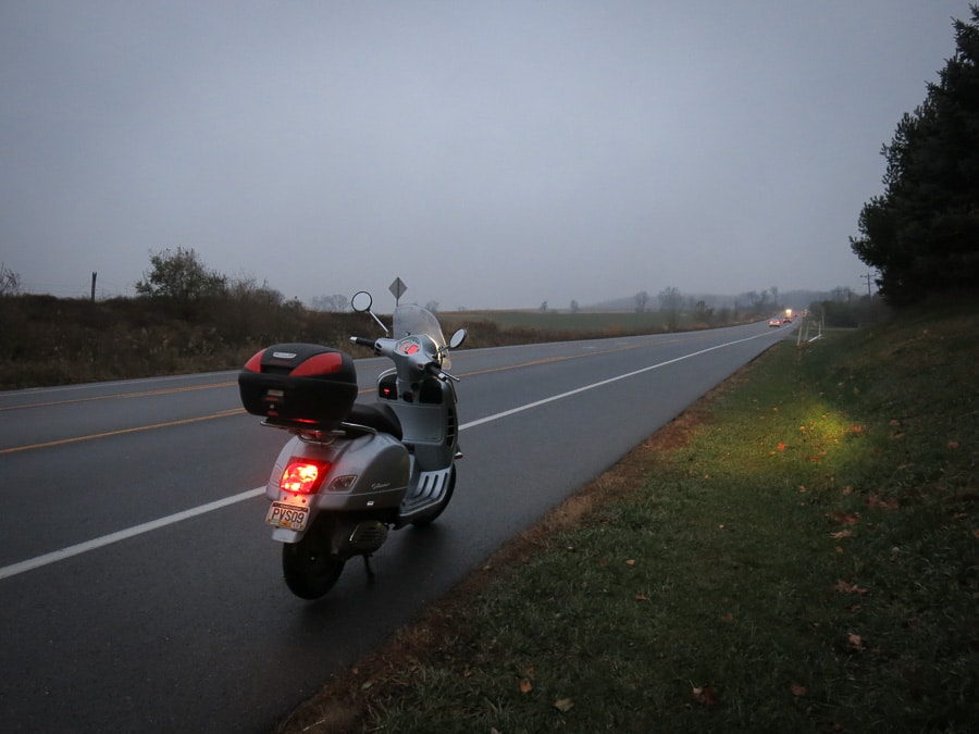 Vespa GTS scooter along the road on a murky morning.