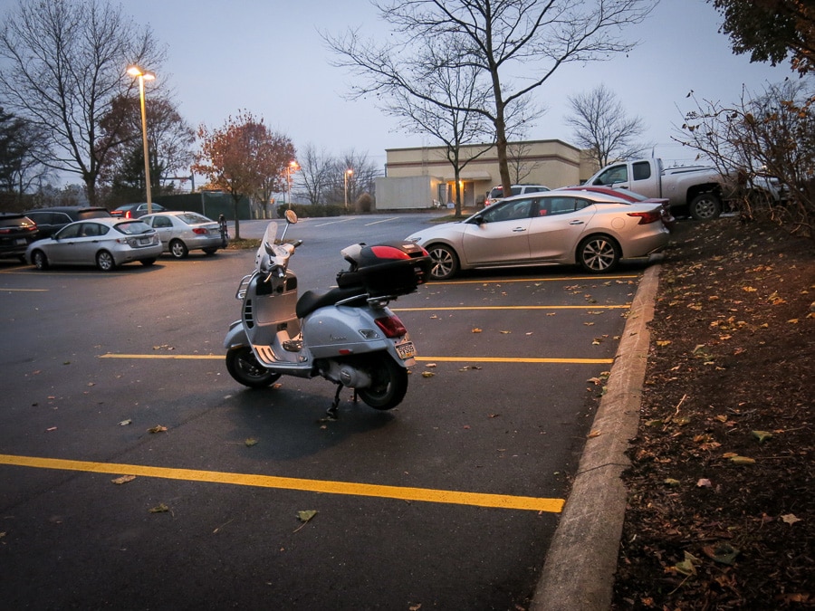 Vespa scooter in a parking lot in early morning on a murky day.
