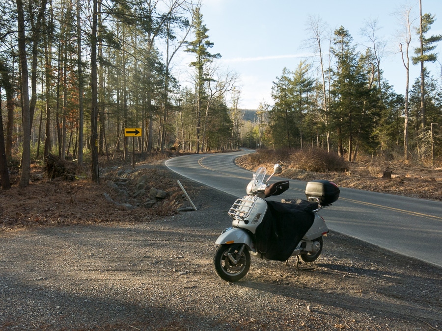 Vespa GTS along a forest lined road.