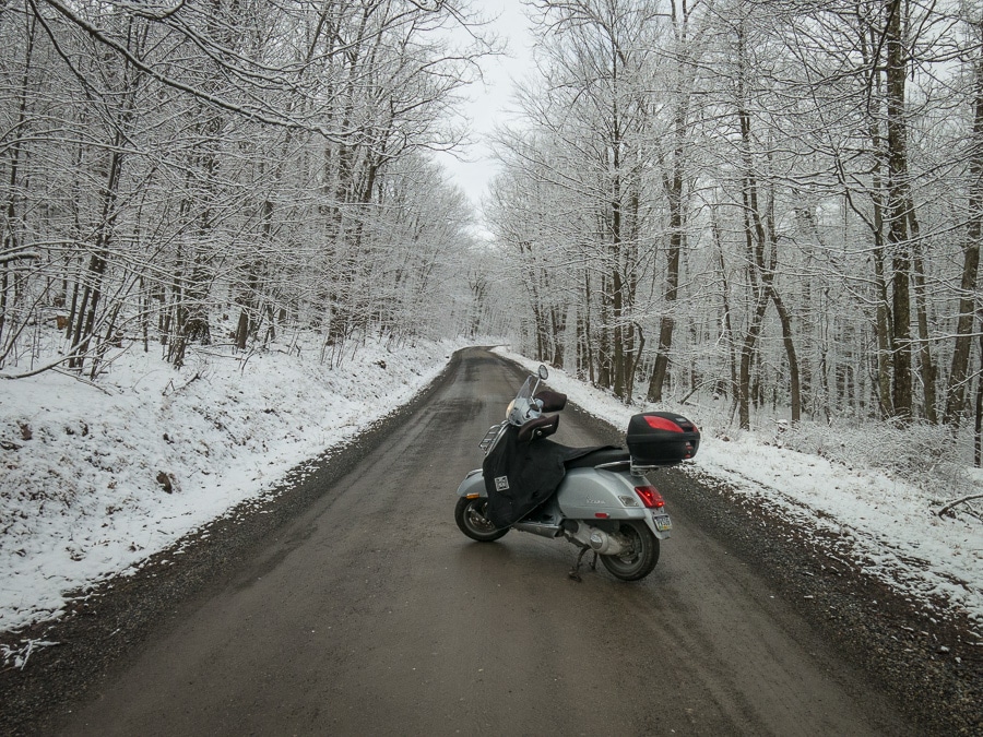 Vespa GTS scooter on a dirt road on a snowy day.