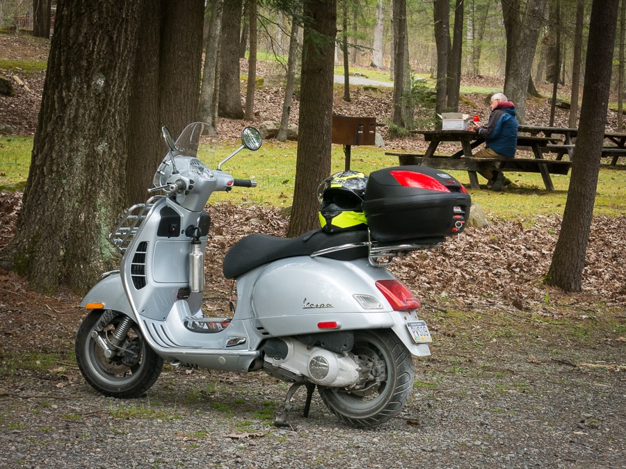 Vespa GTS scooter at a picnic area.