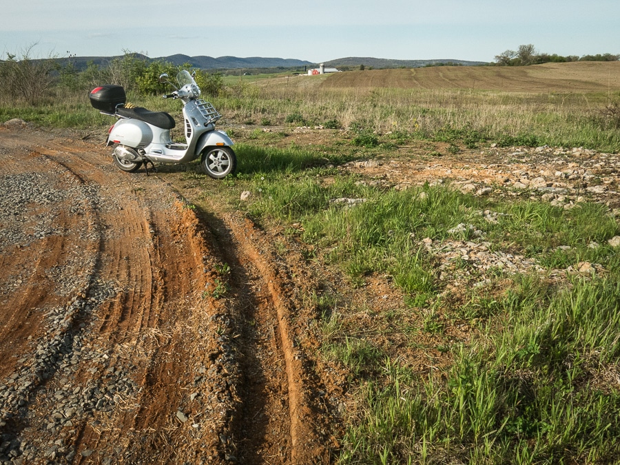 Vespa GTS scooter in muddy field.