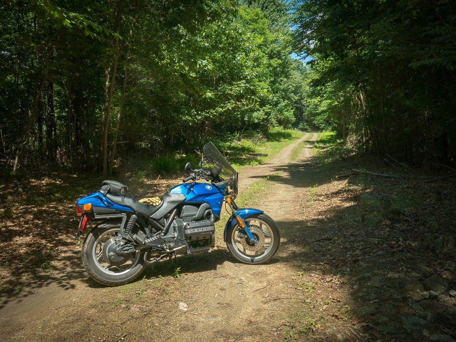 1992 BMW K75 motorcycle on a gravel forest road.