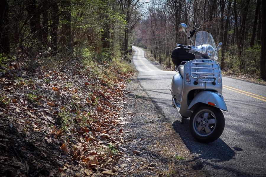Vespa GTS scooter along rural road.