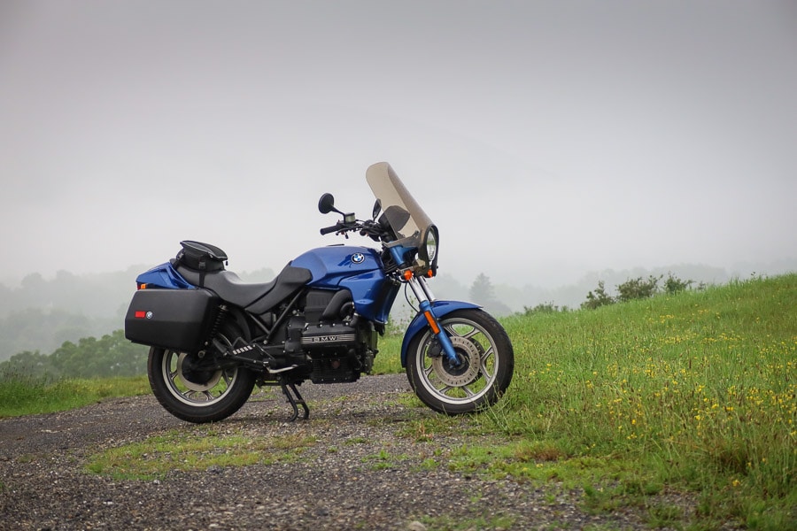 BMW K75 motorcycle parked on a gravel road on a foggy morning.