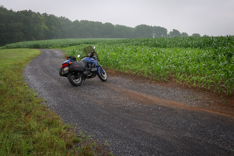BMW K75 motorcycle on a gravel farm road.