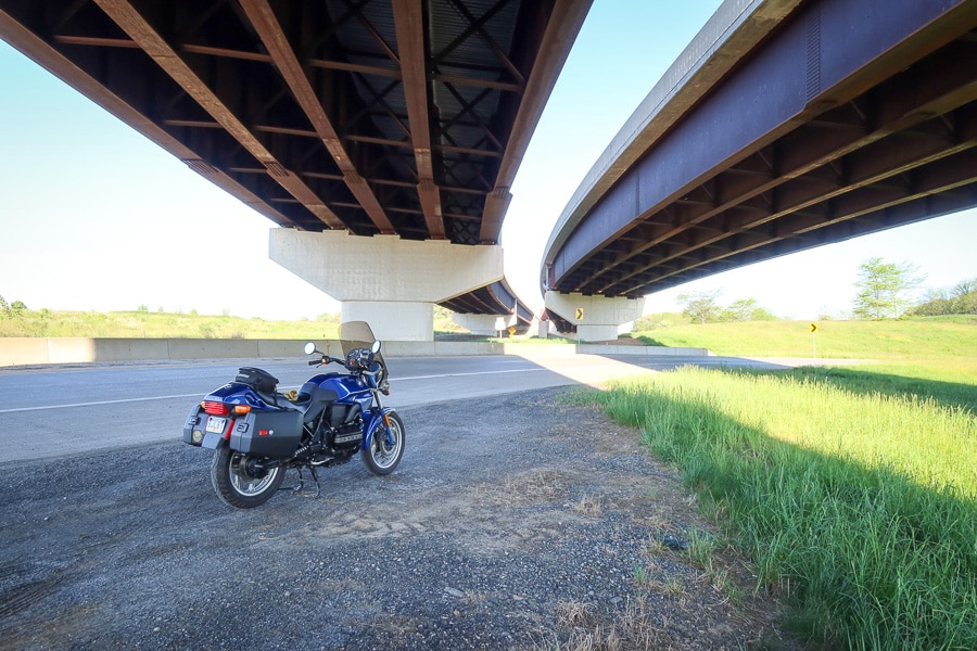 BMW K75C motorcycle parked beneath a freeway overpass.