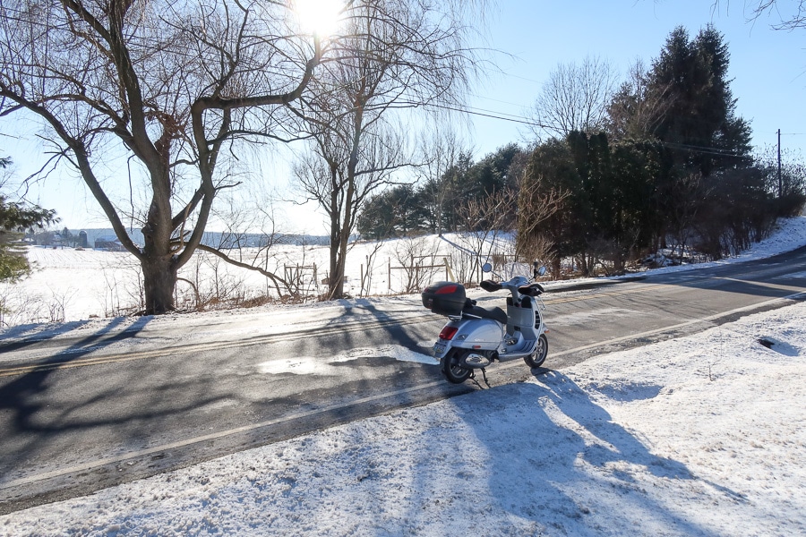 Vespa GTS scooter riding through a snow covered landscape