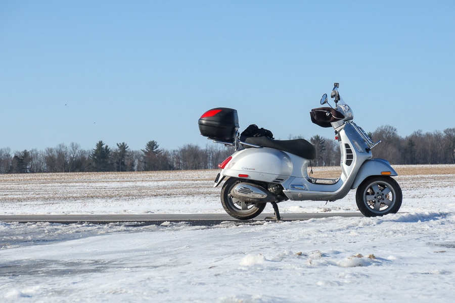 Vespa GTS scooter on a rural road in winter.