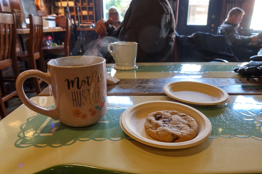 A cup of hot tea and a cookie on a table in a cafe.