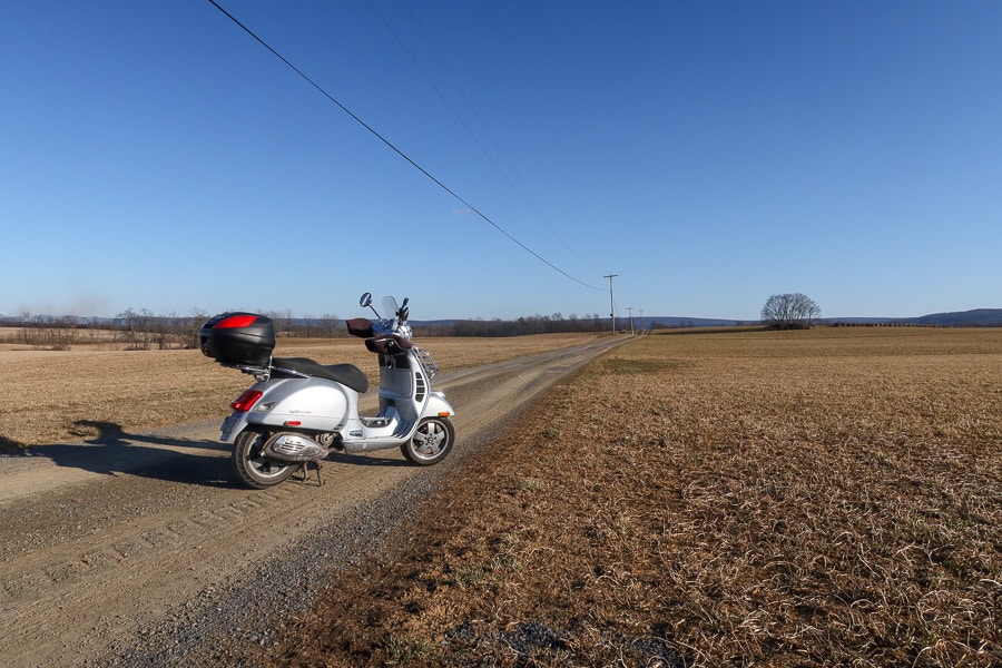 Vespa GTS 250 scooter parked on a farm lane.