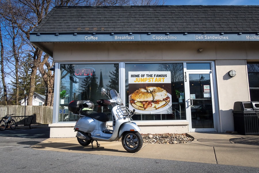 A Vespa GTS 250 scooter is parked in front of the Pump Station Cafe.