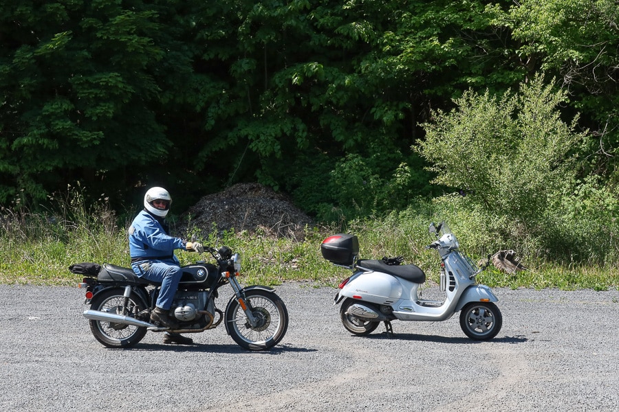 A Vespa GTS scooter riding with a vintage BMW.