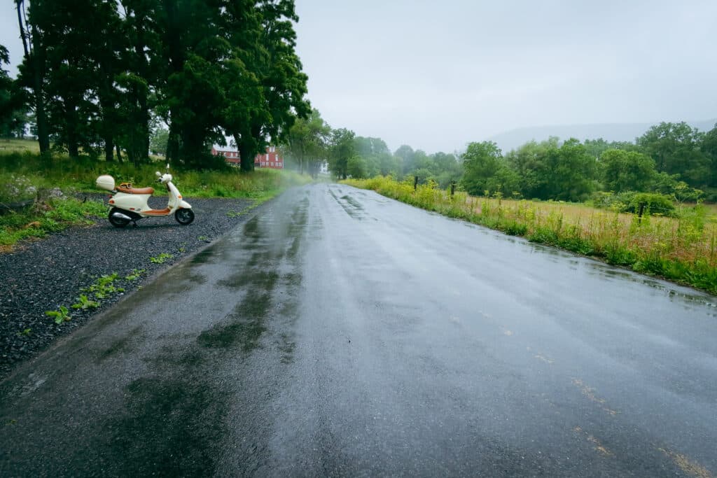 Vespa ET4 scooter along a wet rural road.