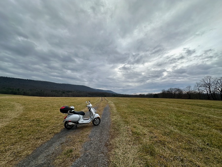 Vespa GTS 250 scooter on a rural landscape.