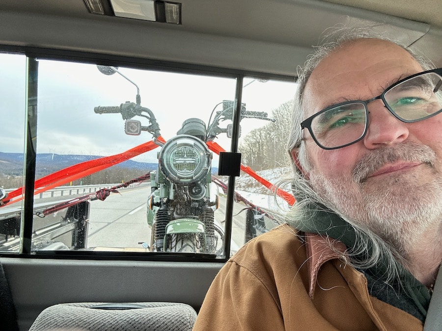 Steve Williams riding in a truck with his new 2023 Honda CT125 Trail strapped down in the bed behind him.