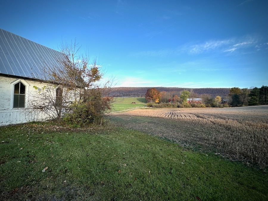 View past an old church towards open fields of a farm.