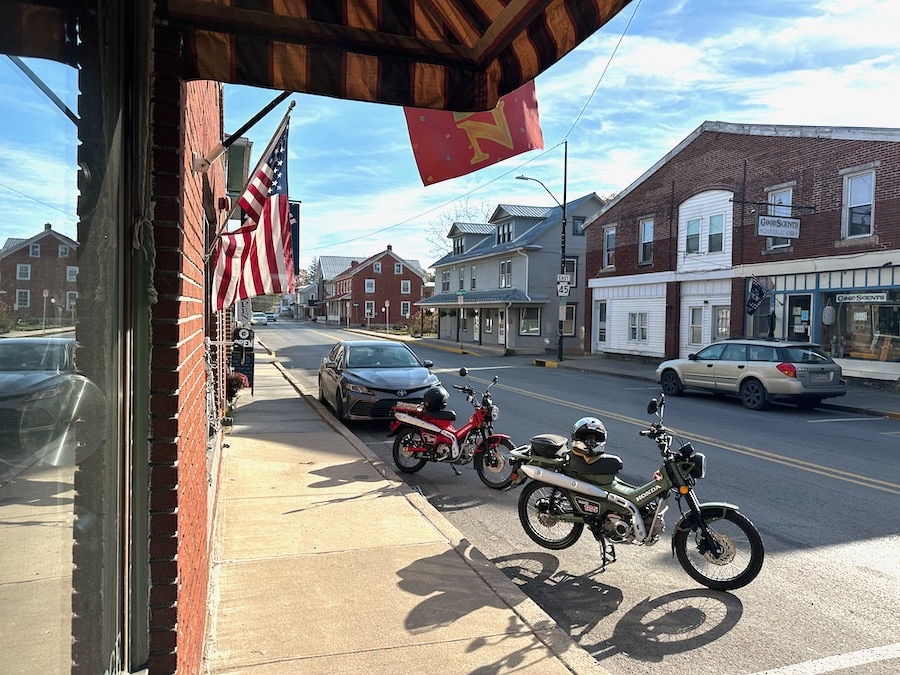 Two Honda Trail 125 motorcycles parked along the street in Millheim, Pennsylvania.