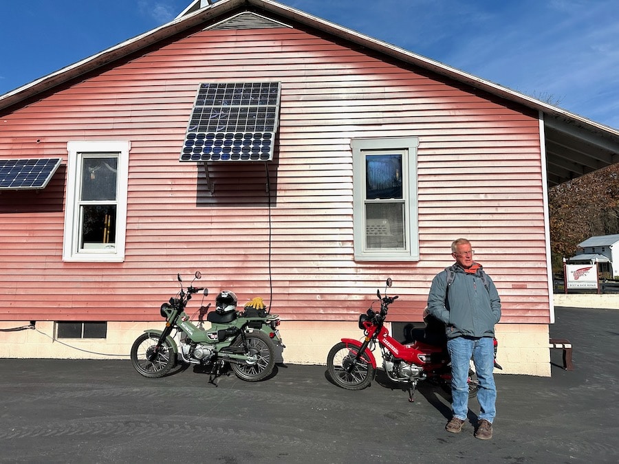 Man standing next to two Honda Trail 125 motorcycles.