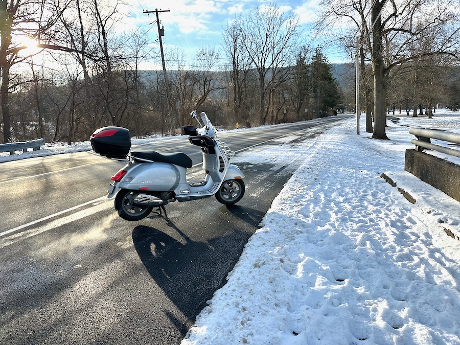 Vespa GTS scooter along a road in winter.