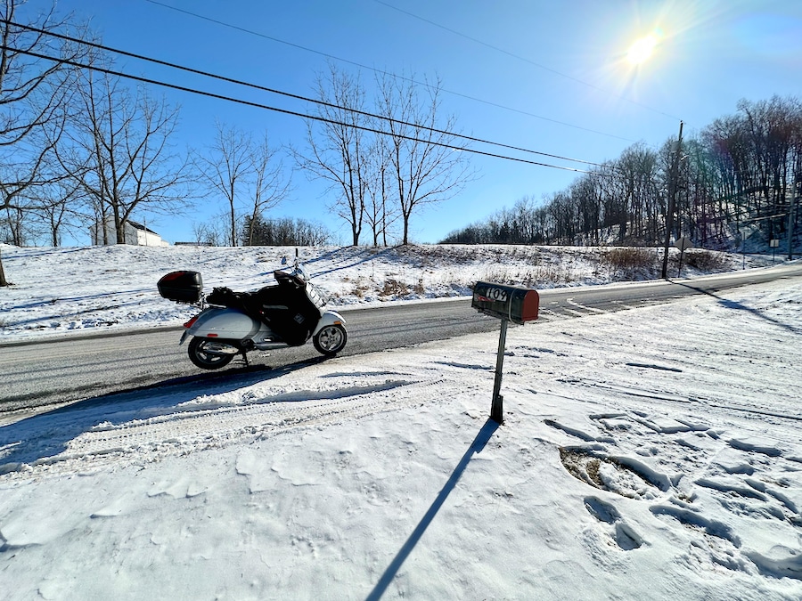 Vespa GTS scooter parked along a road in winter.