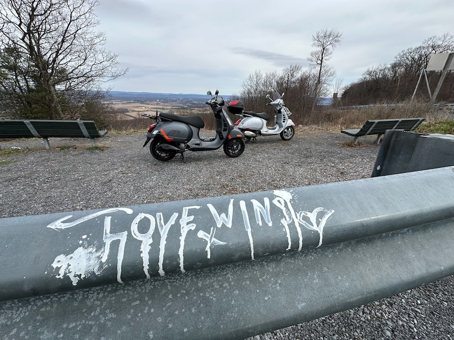 Vespa scooters parked at a scenic vista.