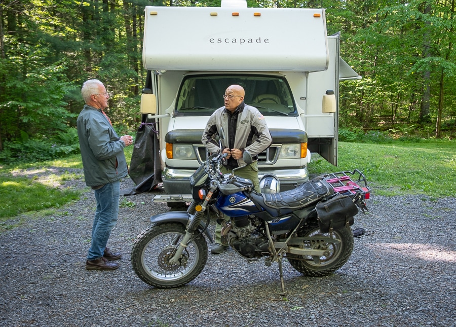 Two men with a Yamaha TW200 motorcycle.