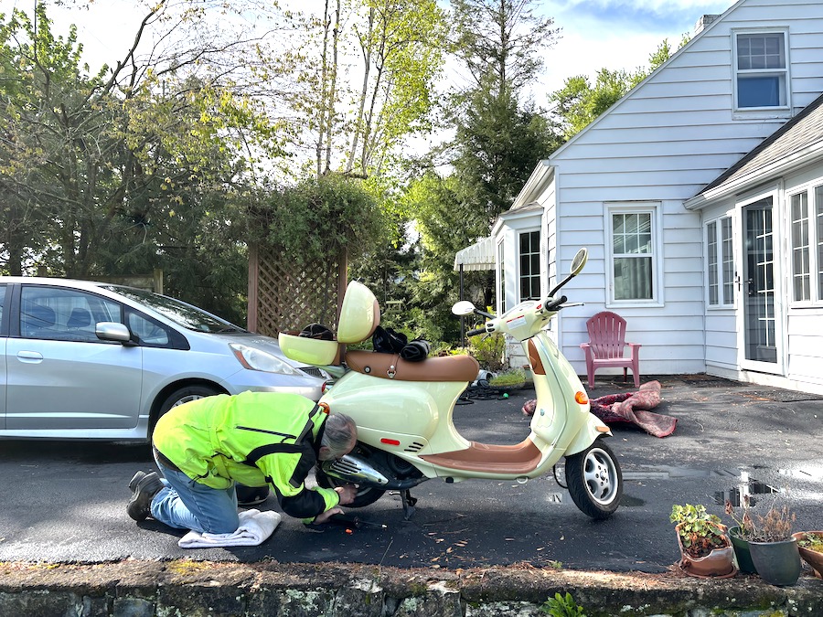 Man checking the rear wheel tire pressure on a Vespa ET4 scooter.