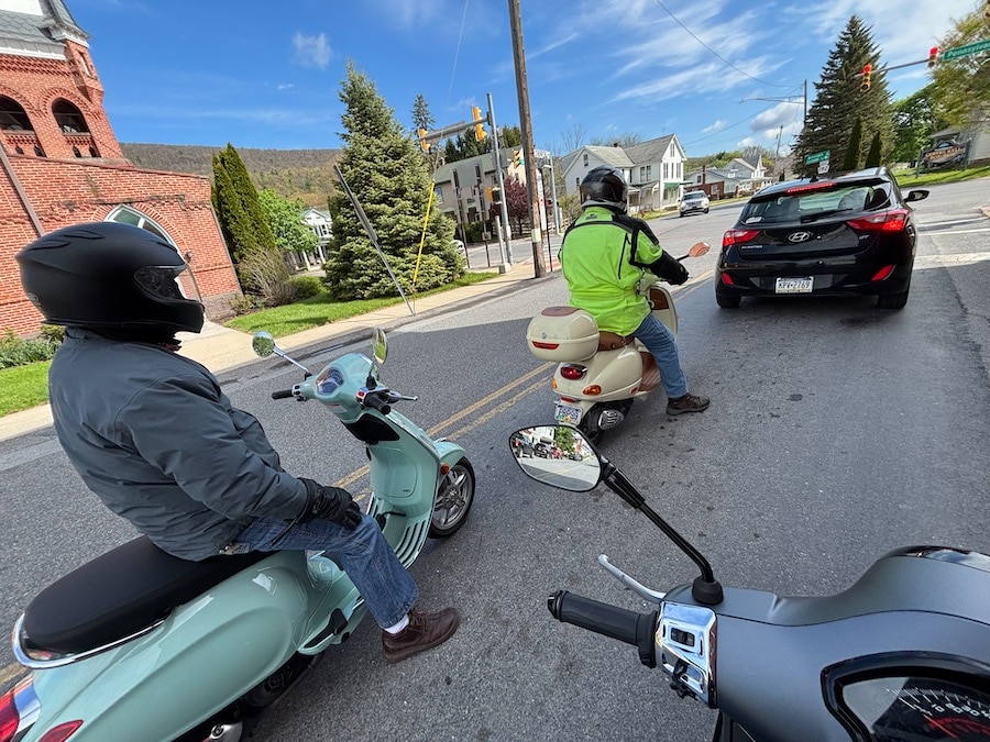 Vespa scooters stopped at an intersection.