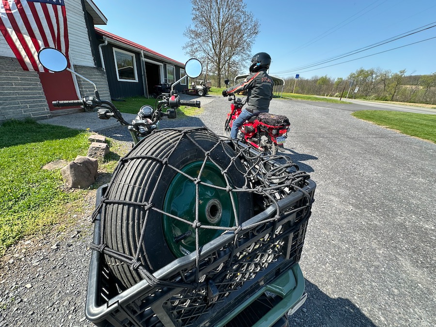A wheelbarrow tire in the milk crate on the back of a Honda Trail 125 motorcycle.