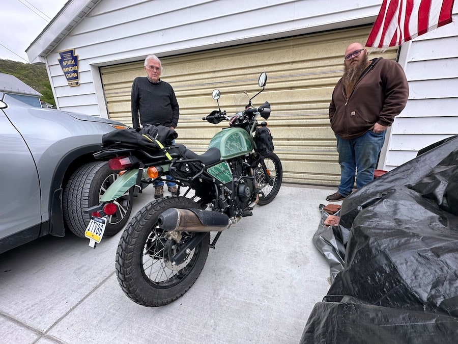 Two men standing next to a 2022 Royal Enfield Himalayan motorcycle.
