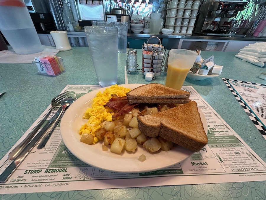 A plate of bacon, eggs, potatoes, and toast.