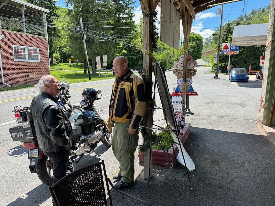 Two men talking in front of motorcycles at a General Store.