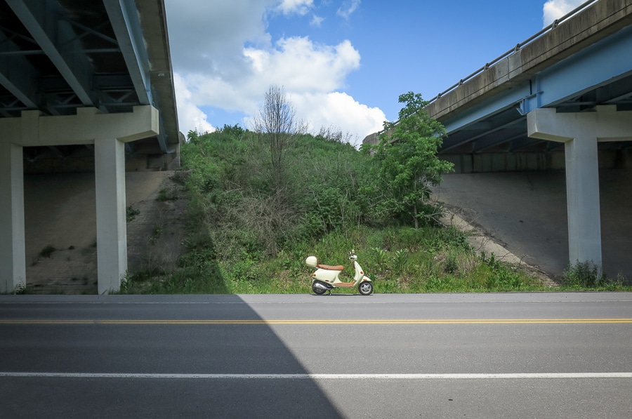 A 2004 Vespa ET4 scooter parked under a highway overpass.